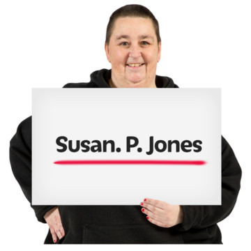 A woman holding a sign with her name written on it and underlined.