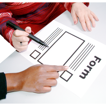 People writing on a a paper form on a table