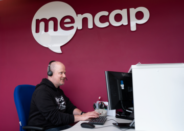 Helpline adviser on the phone whilst using a computer