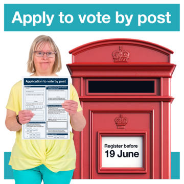 A woman with a postal vote form standing next to a postbox.