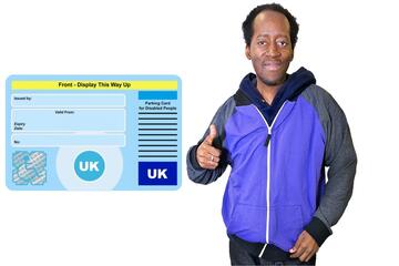 A man standing beside a Blue Badge with his thumb up.