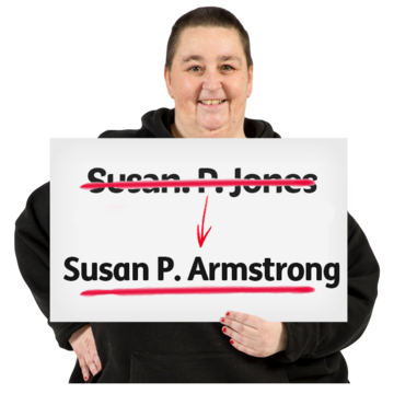 A woman holding a sign with her old name crossed out, and an arrow to her new name underlined in red
