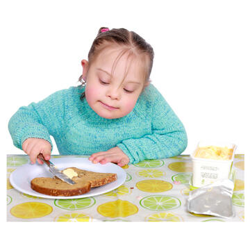 A young girl holding spreading butter on some bread.