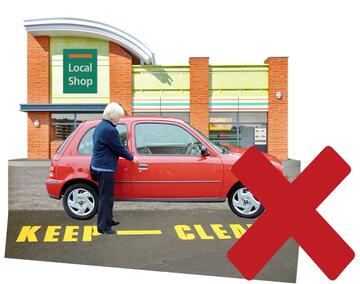 A red cross beside a car which is parked by a keep clear sign.