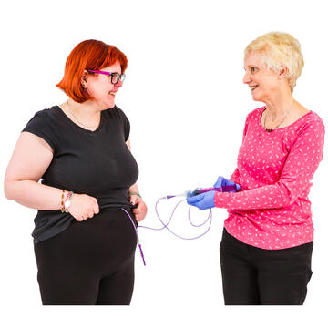 A lady holding a feed bag with the tube going to another lady's stomach.