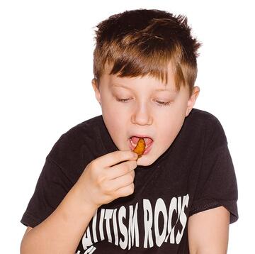 A boy putting a chip in his mouth.