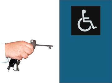 A hand holding a radar key and a door with a wheelchair sign on it.