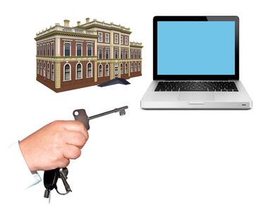 A hand holding a radar key and a laptop and a building.