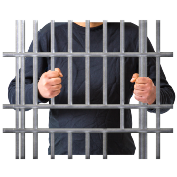 A person standing behind prison bars holding on to them