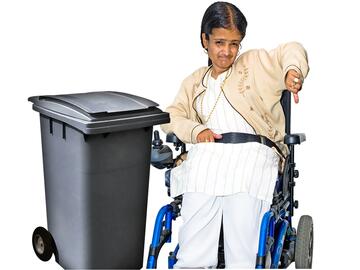A wheelie bin and a woman in a wheelchair beside the bin with her thumb pointing down.
