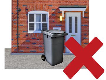 A house with a wheelie bin outside it and a red cross.