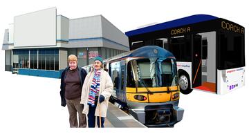 2 people standing in front of a shop, a train and a coach.