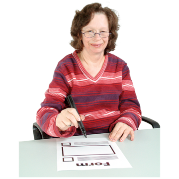 A woman sitting at a desk with a pen in her hand about to fill out a form