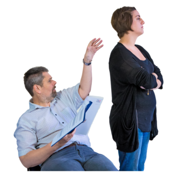 A man is sitting down trying to get the attention of a support worker who is ignoring him