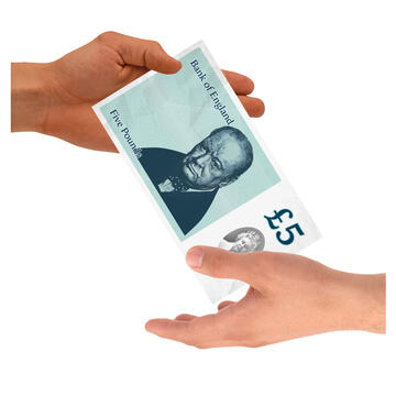 A five pound note being passed from one person to another.
