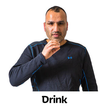 A man signing drink in BSL by making a cup shape with his hand and holding it up towards his mouth.