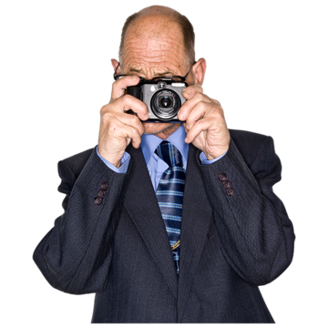 A man in a suit holding a camera to his face to take a picture