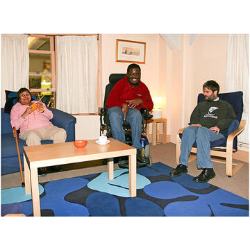 3 people sitting around a coffee table in a lounge in a house.