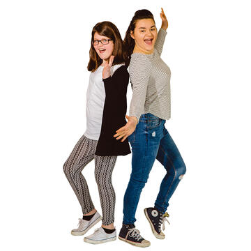 Two teenage girls standing back to back and posing for the camera.
