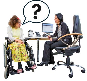A lady sitting at a desk by a computer screen looking at a lady in a wheelchair who has a speech bubble with a question mark in it.