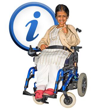 A lady in a wheelchair smiling with her thumb up and an information sign behind her.