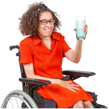 A lady in a wheelchair holding a glass of water.