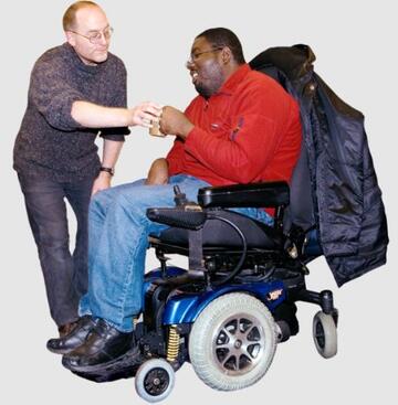 A man is giving a man in a wheelchair a cup of tea