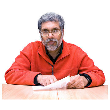 A man sitting at a table holding a piece of paper and thinking.