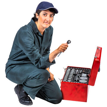 A woman in overalls kneeling beside a toolbox.