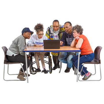 A group of people sitting at a table looking at a laptop.