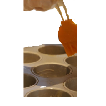 A bun tin and a brush above it covered in melted butter.