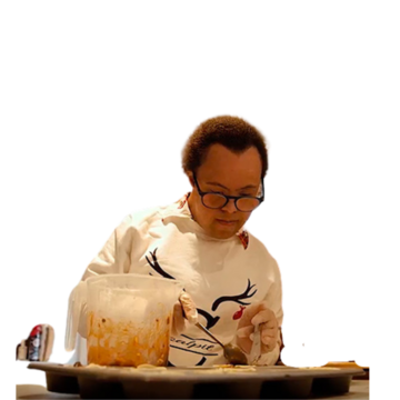 Michael using a spoon to fill a bun tin with mixture.
