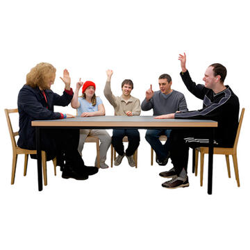 A group of people sitting around a table.  Each person has a hand up to vote.