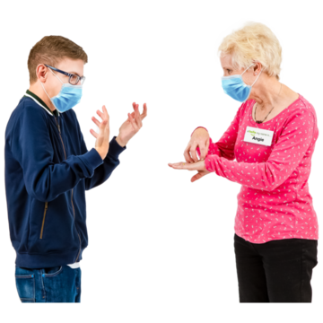 A woman using sign language to a young man. Both are wearing face masks