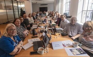 The board of trustees for Mencap sitting around a long rectangular meeting table