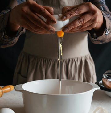 Someone breaking an egg into a bowl