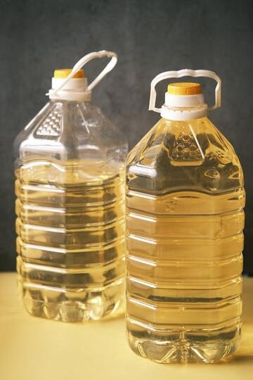 two clear plastic bottles with yellow oil inside