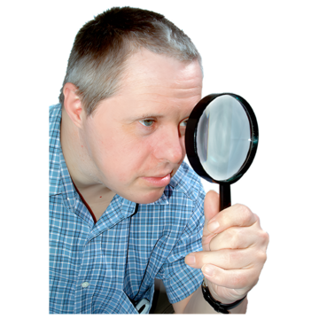 A man looking through a magnifying glass while wearing a blue checked shirt.