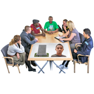 A group of people sitting around a table having a discussion. On the table is a picture of a young person and gravestone