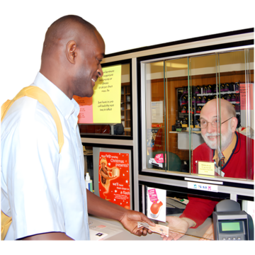 A man paying in some money to someone behind glass 