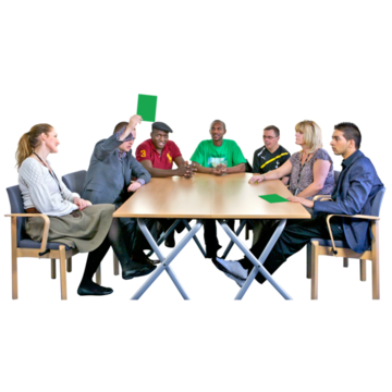 7 people sitting around a meeting table. One person is raising a green card.