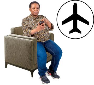 A woman sitting looking at her phone with an aeroplane image in a circle beside her.