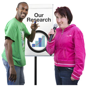 2 people standing in front of a flipchart which says our research.