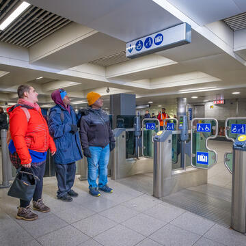3 people looking at a sign in a tube station.