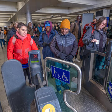 A person walking through a gate in a station with lots of people behind them.
