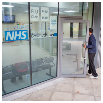 A photograph of a person entering an NHS building