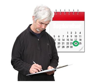 A man signing something on a clipboard.  Behind him is a calendar with a ring around a date.