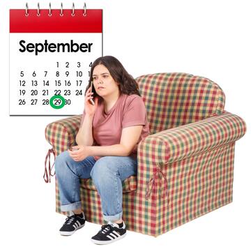 A woman sitting in a chair having a phone call.  A calendar is behind her with a date circled on it.