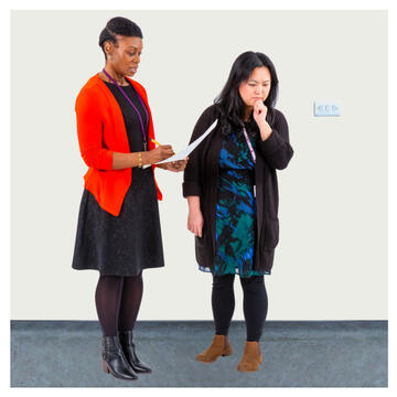 A woman with a clipboard and a woman looking thoughtful and looking at the room.