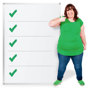 A woman smiling and with her thumb up standing beside a list with green ticks.
